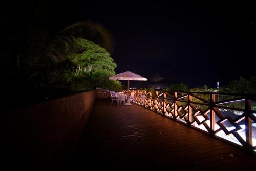 a boardwalk with chairs and an umbrella at night at PERLA Dhangethi in Dhangethi