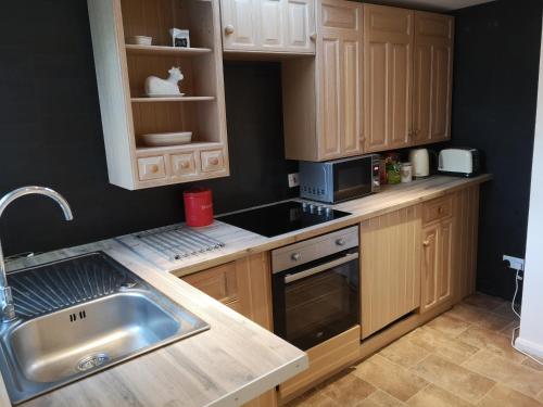 a kitchen with wooden cabinets and a sink at Blair Drummond Holiday Home in Doune