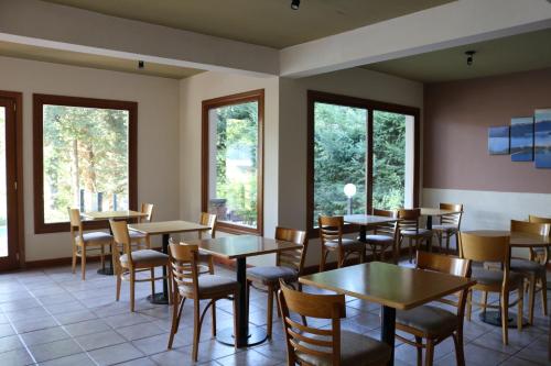 Un restaurante con mesas, sillas y ventanas. en Hosteria Las Garzas, en Villa La Angostura