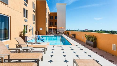 eine Terrasse mit einem Pool und Stühlen sowie ein Gebäude in der Unterkunft Holiday Inn Express Fort Lauderdale Airport South, an IHG Hotel in Dania Beach