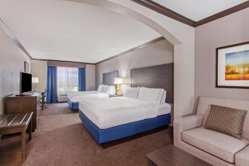 a hotel room with two beds and a chair at Holiday Inn Express & Suites Wharton by IHG in Wharton