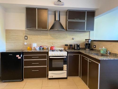 a kitchen with black cabinets and a stove top oven at Mendoza Apartments Ezeiza Airport in Luis Guillón