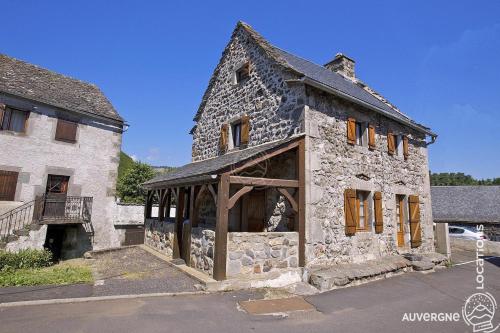 an old stone building with a woodenovation on the front at Le Jassaguet in Murol