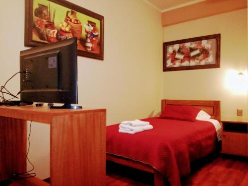 a bedroom with a bed with a red blanket and a tv at Hostal Cagnapa Restobar in Uyuni