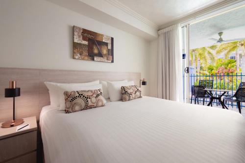 a bedroom with a large white bed and a window at Silkari Lagoons Port Douglas in Port Douglas