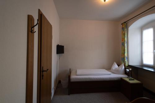 Habitación pequeña con cama y ventana en Bistro-Pension Vis-a-Vis, en Vohburg an der Donau