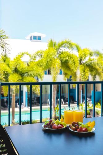 two plates of fruit on a table with a view of a pool at Silkari Lagoons Port Douglas in Port Douglas