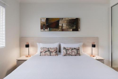 a bedroom with a white bed with two lamps at Silkari Lagoons Port Douglas in Port Douglas