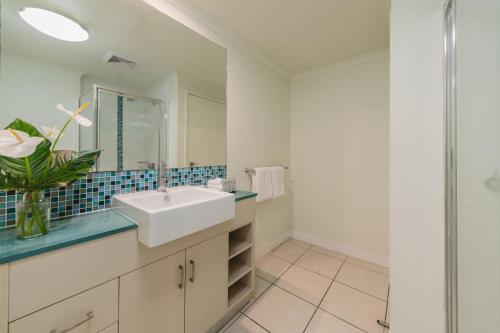 a white bathroom with a sink and a shower at Silkari Lagoons Port Douglas in Port Douglas