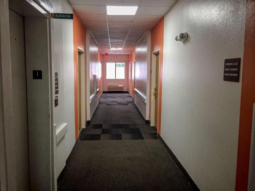 a long hallway with orange walls and a checkered floor at Motel 6-Woodway, TX in Woodway