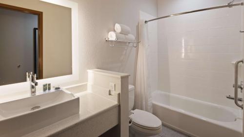 a white bathroom with a toilet and a sink at Best Western Green Oaks Inn in La Vernia