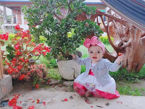 a little girl sitting on the ground next to a tree at Cabañas Guacari San Agustín huila in San Agustín