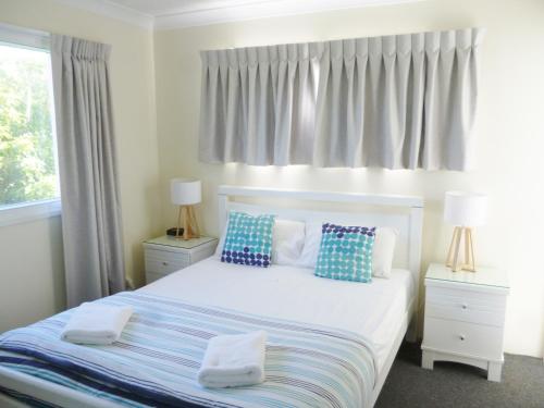 um quarto com uma cama com almofadas azuis e brancas em Le Lavandou Holiday Apartments em Gold Coast