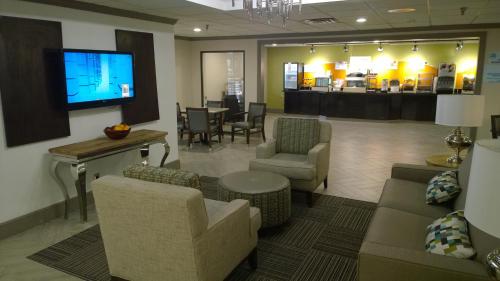 a waiting room with couches and chairs and a tv at Holiday Inn Express & Suites Fayetteville University of Arkansas Area by IHG in Fayetteville