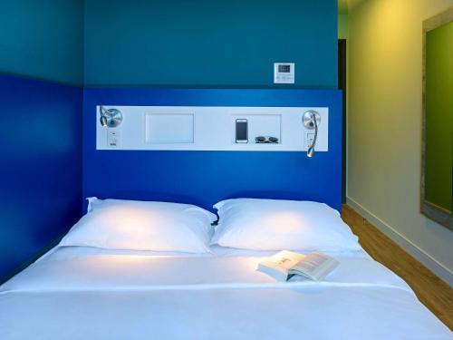 a bed with a blue head board with a book on it at ibis budget Santos Gonzaga in Santos