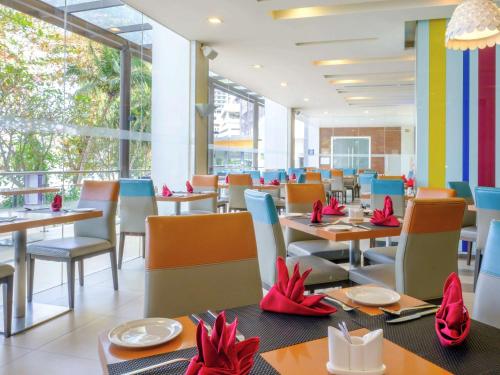 a restaurant with tables and chairs with red bows on them at Mercure Penang Beach in George Town