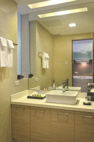 a bathroom with a sink and a large mirror at Valero Grand Suites by Swiss-Belhotel in Manila