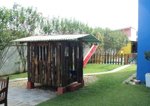 a wooden play structure with a slide in a yard at Pousada Recanto Dom Arthur in Itapema