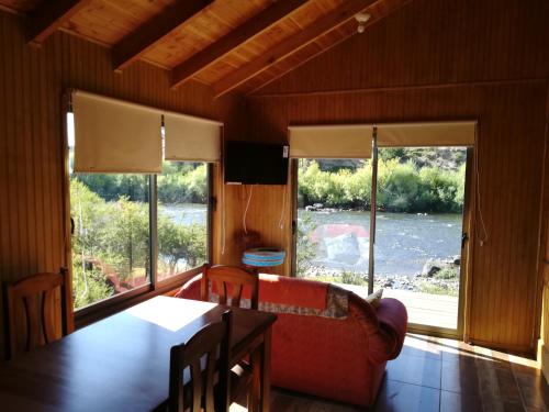 a living room with a couch and a table and windows at Cabañas Tela in Lonquimay