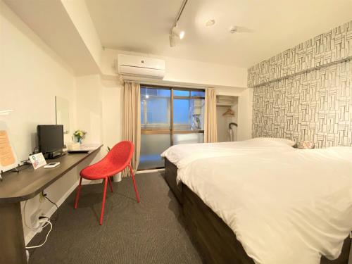 a bedroom with a bed and a desk and a red chair at BEEHIVE APARTMENT Moriguchi in Osaka