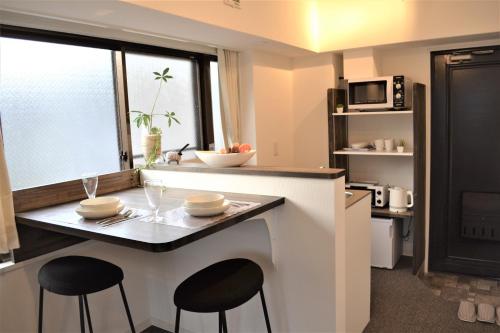 a kitchen with a counter with two stools and a table at BEEHIVE APARTMENT Moriguchi in Osaka