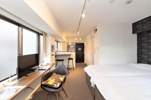 a bedroom with a bed and a tv and a chair at BEEHIVE APARTMENT Moriguchi in Osaka