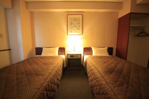 a hotel room with two beds and a lamp at Chofu Urban Hotel in Chofu