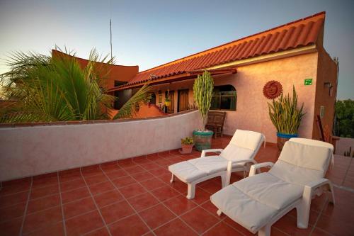 a patio with two white chairs and a house at Hotel Posada Luna Sol in La Paz