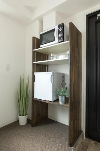 a room with a shelf with a microwave on it at BEEHIVE APARTMENT Moriguchi in Osaka