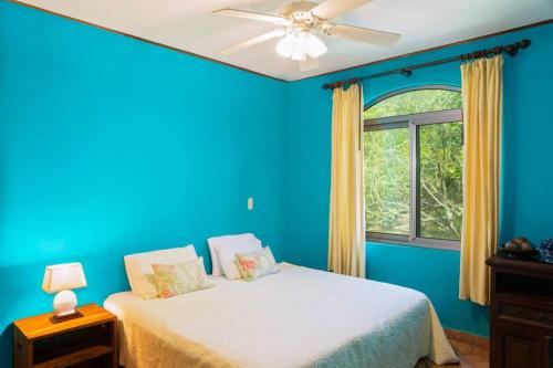 a blue bedroom with a bed and a window at Villas Iguana A-2 Beachfront Condo in Rivas