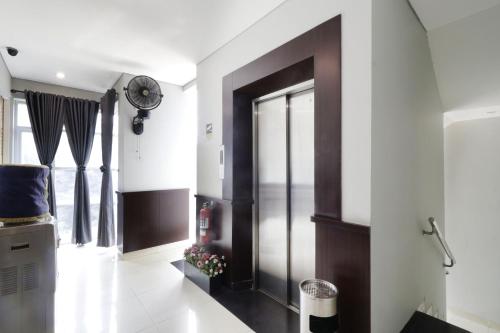 um corredor com paredes brancas e uma grande porta de vidro em WISMA 9 Jakarta em Jacarta