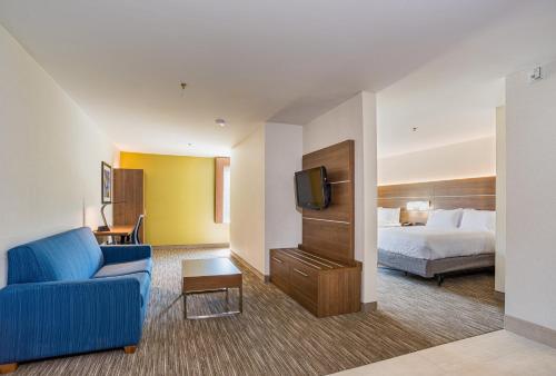 a hotel room with a bed and a blue couch at Holiday Inn Express Hotel & Suites Swansea by IHG in Swansea