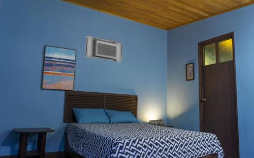 a blue bedroom with a bed and a window at Casa Garrobo in Los Cóbanos