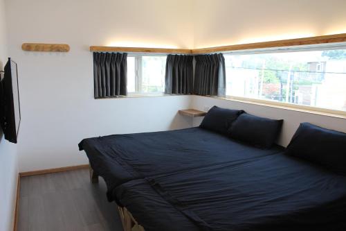 a bed in a room with a window and a couch at Summerflow Hostel in Xiaoliuqiu