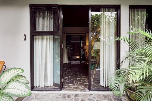an open door of a house with plants at Outpost Ubud Penestanan in Ubud