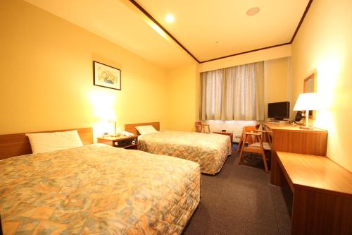 a hotel room with two beds and a desk at New Gifu Hotel Plaza in Gifu