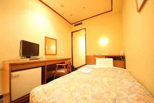 Habitación con cama y escritorio con TV. en New Gifu Hotel Plaza en Gifu