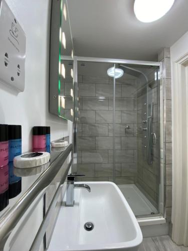 a bathroom with a shower and a white sink at The Charles Hotel in Chatham