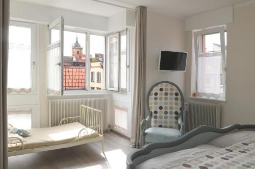 une chambre avec un lit, une chaise et des fenêtres dans l'établissement Les ARTISANS au centre historique, à Colmar
