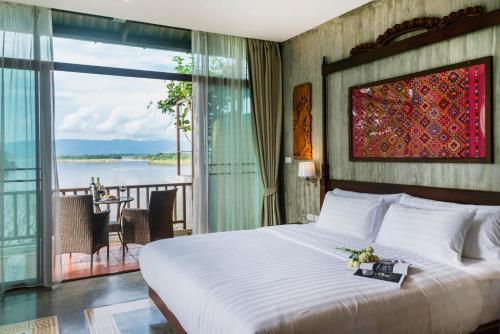 Schlafzimmer mit einem Bett und Blick auf das Wasser in der Unterkunft Bansaeo Garden and Resort in Chiang Saen