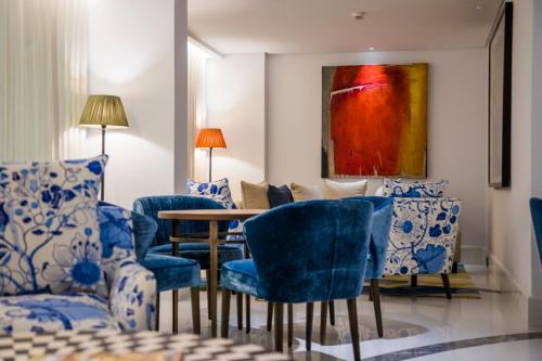 a room with blue chairs and a table and a painting at The Merchant House in Manama