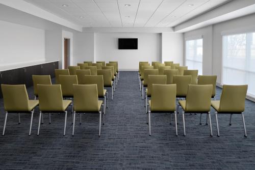 an empty room with chairs and a screen at Holiday Inn Express & Suites - Elkhorn - Lake Geneva Area by IHG in Elkhorn