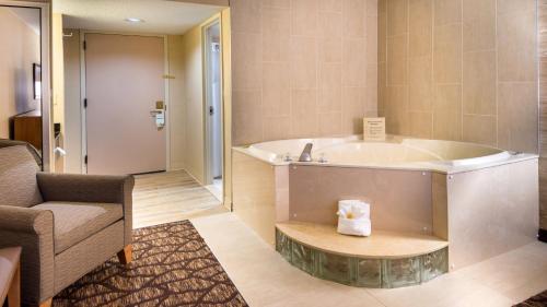 ウォーレンにあるHoliday Inn Hotel & Suites Warren by IHGの椅子とソファ付きの客室内のバスタブ