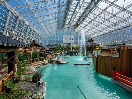 uma piscina de água num edifício com tecto de vidro em Kirishima Hotel em Kirishima