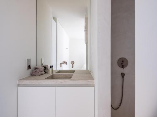 ein weißes Badezimmer mit einem Waschbecken und einem Spiegel in der Unterkunft Maison N in Gent