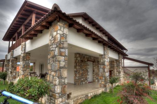 a stone house with a stone pillar and a porch at Toula Rooms in Ángistron