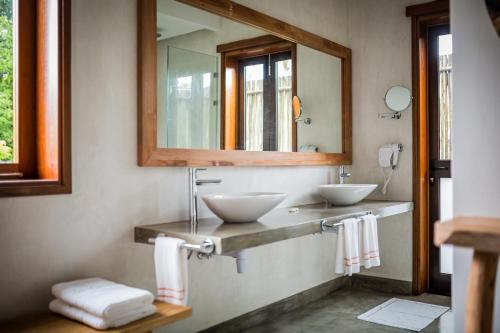 a bathroom with a sink, mirror and tub at Les Lauriers Eco Hotel in Anse Volbert Village