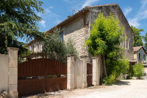a brick house with a gate and a tree at Hôtel Mas Vidau Porte des Alpilles in Saint-Étienne-du-Grès