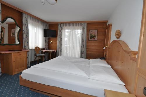 a bedroom with a large white bed and a desk at Hotel Stülzis in Lech am Arlberg