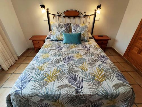 um quarto com uma cama com um edredão azul e amarelo em Royuela Hostal em Royuela